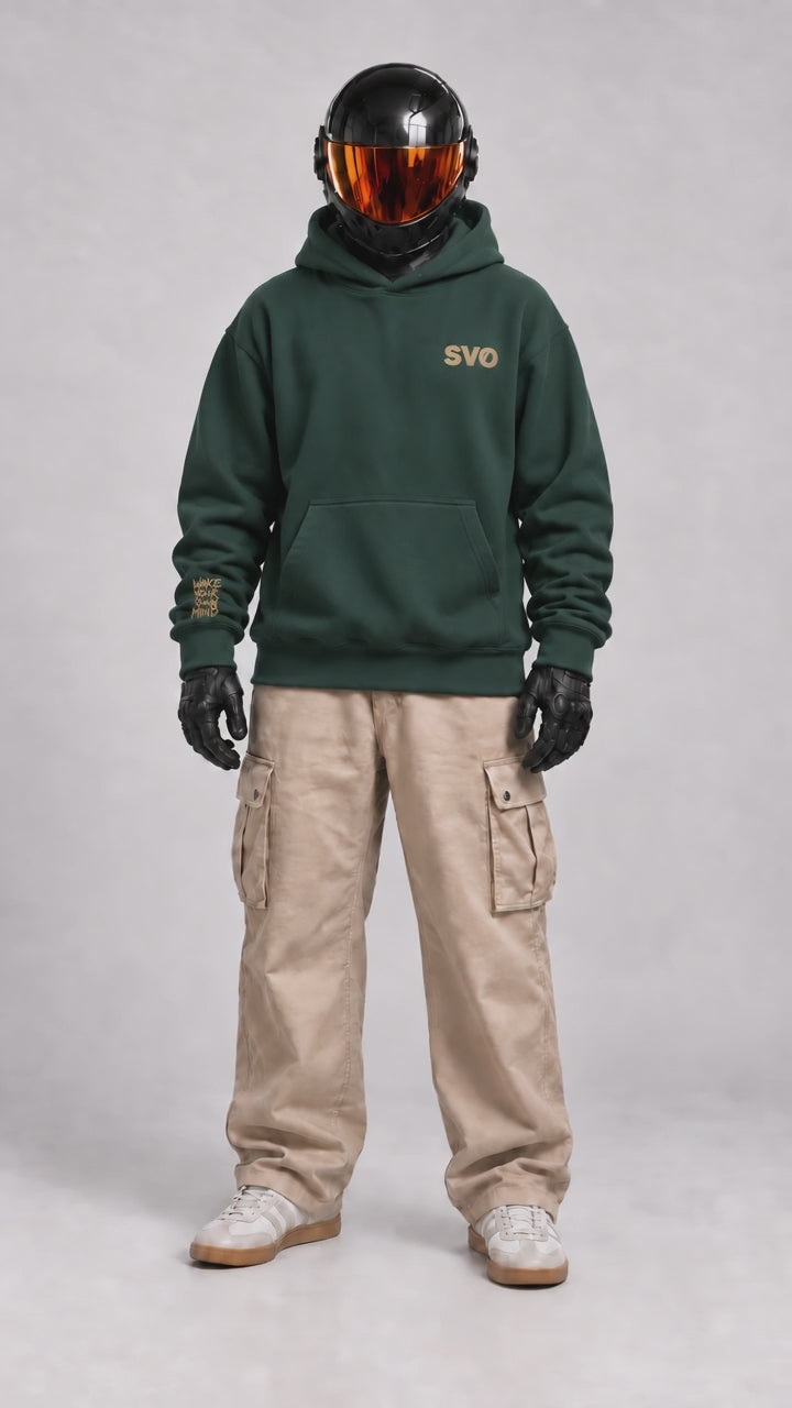 Front view of SVO wearing the pine green SVO oversized hoodie with beige cargo trousers.