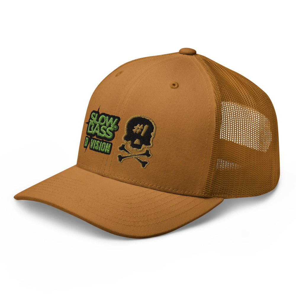 Three-quarter front view of the caramel SBD #1 trucker cap, featuring the green SLOW BASS D/VISION logo, skull emblem and mesh side panels.